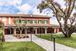 una casa arancione con un albero di fronte di Hotel Residence - Il Giardino del Cigno a Latisana