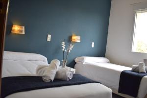 a room with three beds with towels and a vase with flowers at Hotel El Ancla in Villanueva de la Cañada