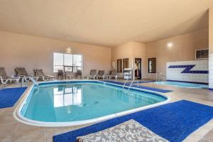 Una piscina en una habitación grande con sillas y mesas. en Comfort Inn Grand Island North, en Grand Island