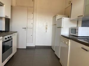 cocina con armarios blancos y nevera blanca en Olaias Signature Apartment, en Lisboa