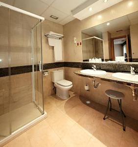 a bathroom with a shower and two sinks and a toilet at Hotel Imperial in Valladolid