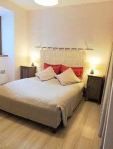 - une chambre avec un grand lit blanc et des oreillers rouges dans l'établissement Gite des Gorges de l'Ardèche, à Chame
