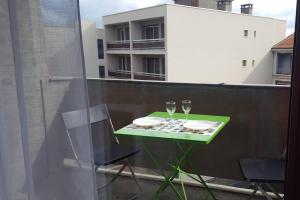 a green table with two wine glasses on a balcony at loft avec parking et terrasse in Chamalières +3 photos
