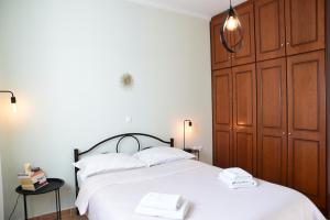 Schlafzimmer mit einem großen weißen Bett und Holzschränken in der Unterkunft Elli Cozy House in Korfu-Stadt