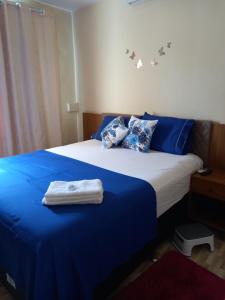 una camera da letto con letto con lenzuola e cuscini blu di Quartos Em Casa Caxias - Pousada Paraíso a Duque de Caxias