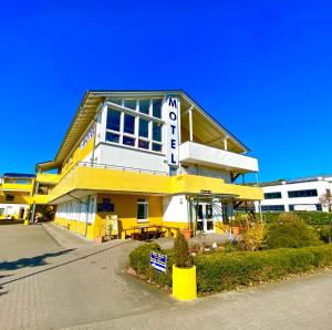 un bâtiment jaune et blanc dans une rue dans l'établissement i-Motel, à Obertshausen