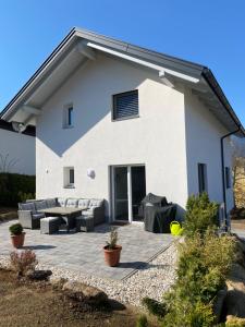 Ein weißes Haus mit einer Terrasse mit Sofas und Frisbee in der Unterkunft Arcana in Seeboden