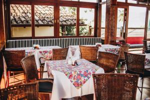 a dining room with tables and chairs and windows at Hotel Fita Azul in Ilhabela