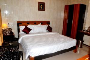 a bedroom with a bed with white sheets and red pillows at Peace Inn Chennai in Chennai