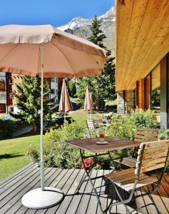 a table and chairs with an umbrella on a deck at Serviced Apartment ELITE in Saas-Fee