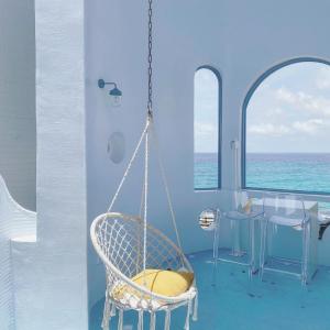 a swinging chair in a room with a table and the ocean at Kenting Met Hi Inn in Eluan