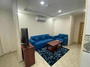 sala de estar con sofá azul y TV en لحظة الاحلام للشقق الفندقية en Makkah