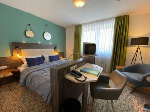 ブルク・アウフ・フェーマルンにあるHafen Hotel Schützenhofのベッド、デスク、椅子が備わるホテルルームです。