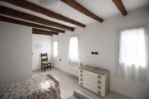 a bedroom with white walls and a bed and a chair at Dimora Marchiada -apeliving- Pellestrina Ve in Pellestrina