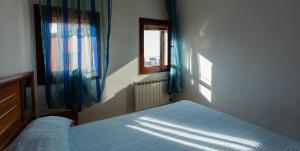 1 dormitorio con 1 cama y una ventana con cortinas azules en Dimora Laguna en Pellestrina