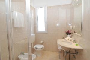 y baño con aseo, lavabo y ducha. en Hotel La Perla, en Lignano Sabbiadoro