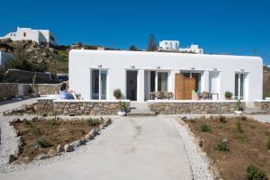 a white house on a hill with a woman sitting in front at Desire Mykonos Apartments in Vrisi/ Mykonos