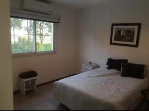 ein Schlafzimmer mit einem weißen Bett und einem Fenster in der Unterkunft Barrio cerrado premium in Dique Luján + 1 Foto