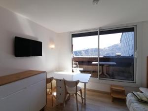 a living room with a white table and a large window at La Godille in Pra-Loup
