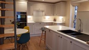 a kitchen with white cabinets and a table and chairs at Riverside Lodge Pied a Terre in Fordingbridge