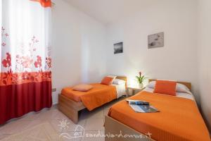 a bedroom with two beds and a red curtain at Casa Acqua Dolce in Cala Gonone