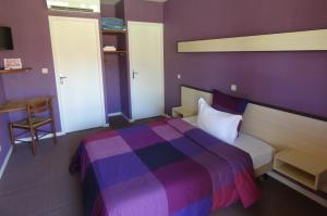 Dormitorio púrpura con cama y mesa en Hôtel L'Agape, en Thermes-Magnoac