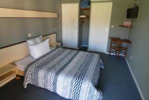 ein Schlafzimmer mit einem Bett, einem Tisch und einem Stuhl in der Unterkunft Hôtel L'Agape in Thermes-Magnoac