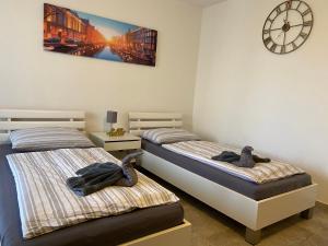 two beds in a room with a clock on the wall at Apartment Hannover in Hannover