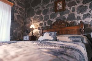 a bedroom with two beds and a stone wall at Baía de Canas Villa in São Roque do Pico