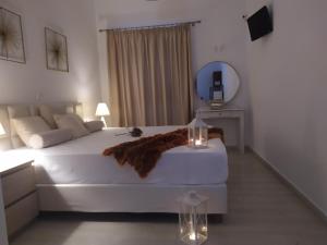een slaapkamer met een groot wit bed en een spiegel bij Aronis Apartments in Benitses