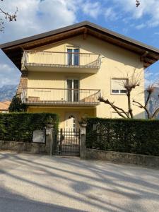 una casa gialla con balcone e recinzione di Casa Bosco a Levico Terme
