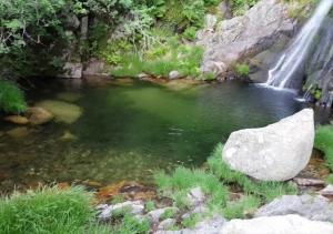 a waterfall next to a river with a large rock at Piscina privada - V3 - Internet Fibra in Teixoso