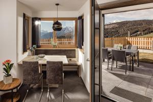 a dining room with a balcony with a table and chairs at Sweet Dolomiti Sonneck in Maranza
