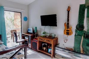 Sala de estar con TV y guitarra en la pared en Lugo`s guest room, en Punta Cana