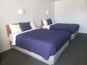 - 2 lits dans une chambre avec des couvertures et des oreillers violets dans l'établissement Aurora Borealis, à Saint-Ignace