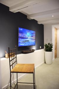 a tv on a wall with a wooden table and a chair at Blueprint B&B - Breakfast & Bikes in Amsterdam