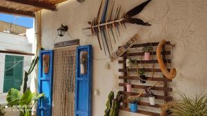 een huis met blauwe deuren en planten aan de muur bij Amélie House in Marsala