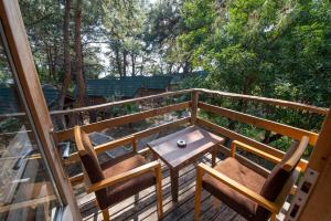 a table and chairs on a deck with trees at Sea Valley Lodge in Faralya