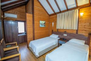 two beds in a room with wooden walls at Sea Valley Lodge in Faralya