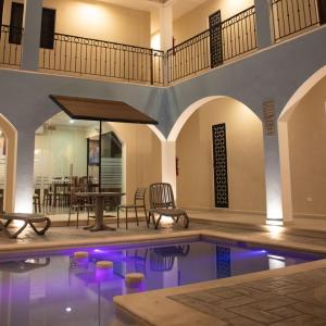 een zwembad in een huis met een tafel en stoelen bij Hotel Las Monjas in Mérida