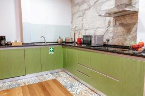a kitchen with green cabinets and a stone wall at Authentic Porto Apartments in Porto