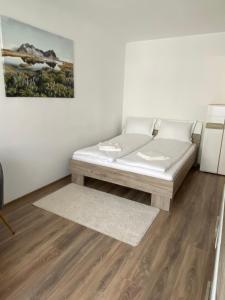 un letto bianco in una camera con pavimento in legno di Focus Home Next a Miercurea-Ciuc