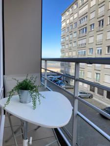 een witte tafel en een plant op een balkon bij Sea Side in Oostende