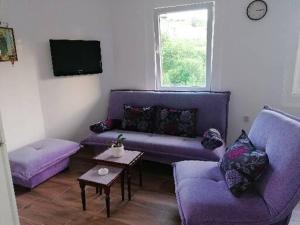 a living room with purple couches and a window at Apartman Gradac Deguric in Valjevo