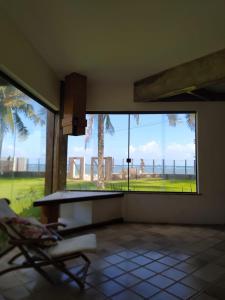 um quarto com uma mesa, uma cadeira e uma grande janela em Casa frente mar com vista incrível! em Vera Cruz de Itaparica