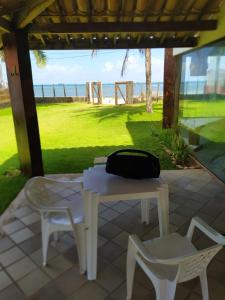 a white table and chairs with a bag sitting on it at Casa frente mar com vista incrível! in Vera Cruz de Itaparica