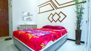 a bedroom with a large bed with a red blanket at Villa Harmoni Syariah by Masterpiece Villa in Karangploso