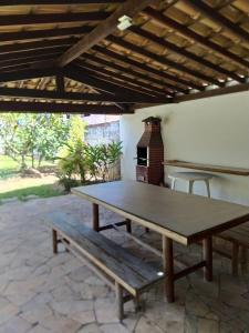 a picnic table with a bench under a roof at Casa frente mar com vista incrível! in Vera Cruz de Itaparica