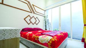 a bedroom with a red bed and a window at Villa Harmoni Syariah by Masterpiece Villa in Karangploso