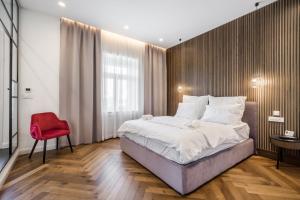 a bedroom with a large bed and a red chair at Budapest Eye- Boutique Suites, by BQA in Budapest